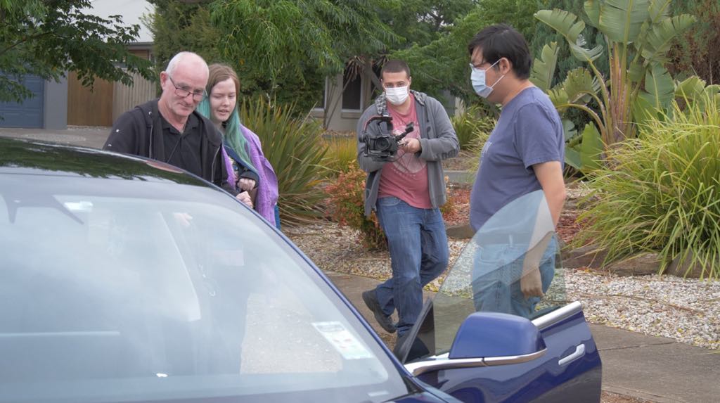 Behind the scenes showing me filming Faith and her father walk towards CheeWei and his Tesla