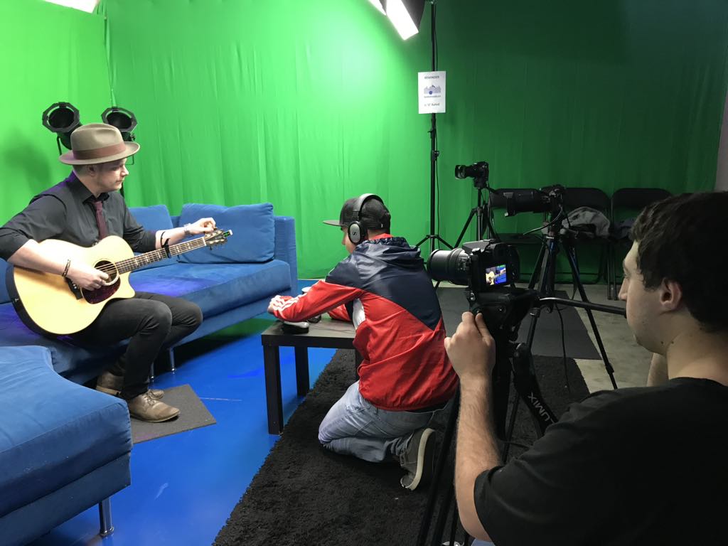 Me using a DSLR in a green screen studio filming Simon Imrei playing a guitar
